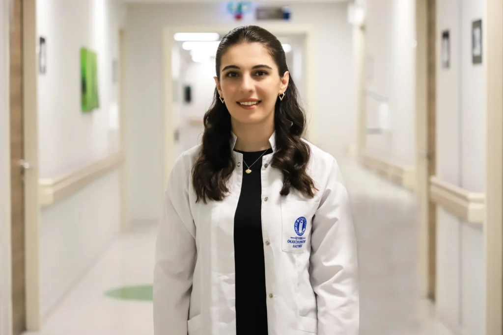 İstanbul Okan Üniversitesi Hastanesi Beslenme ve Diyet Uzmanı İrem Aksoy, hastane koridorunda laboratuvar önlüğüyle gülümseyerek dururken, bağışıklık sistemini güçlendirmenin yolları konusundaki uzman görüşleriyle okuyuculara rehberlik ediyor.