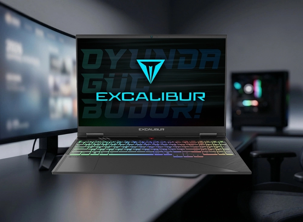 Karanlık bir masada duran, ekranında Excalibur logosu ve Oyunda Güç Budur! ifadesiyle dikkat çeken, renkli RGB aydınlatmalı klavyesi olan metal kasalı bir Casper Excalibur G920 premium oyun laptopu, arkasında bulanık bir monitör ve RGB ışıklı bir masaüstü bilgisayar kulesiyle modern bir gaming kurulumunu sergiliyor.