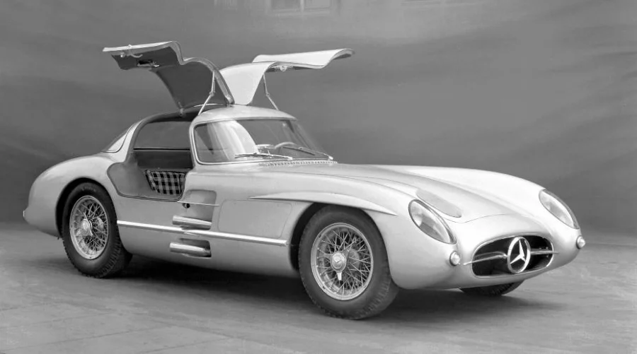 Gümüş renginde, ikonik martı kanat kapıları yukarı doğru açık olan ve dünyanın en pahalı otomobili olarak bilinen Mercedes-Benz 300 SLR Uhlenhaut Coupé'nin net bir şekilde görüldüğü siyah beyaz bir fotoğraf.