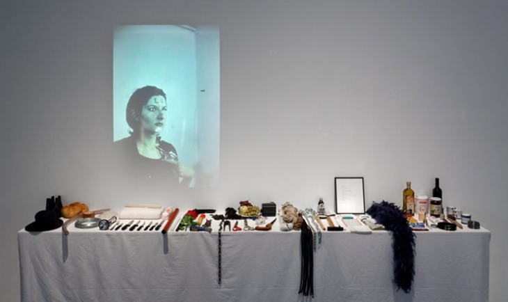 Marina Abramović’in 1974 tarihli Rhythm 0 performansından bir sahne; sanatçının izleyiciye 72 farklı nesneyle etkileşim hakkı tanıdığı, performans sanatının sınırlarını zorlayan efsanevi eseri.
