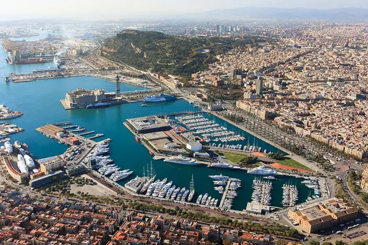 Barselona Port Vell’de demirleyen lüks yatlar ve arka planda tarihi şehir manzarası