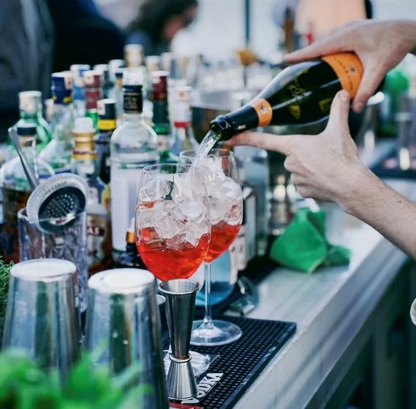 Sail Loft barında, barmenin kırmızı spritz kokteyllerini buz dolu kadehlere hazırladığı an.