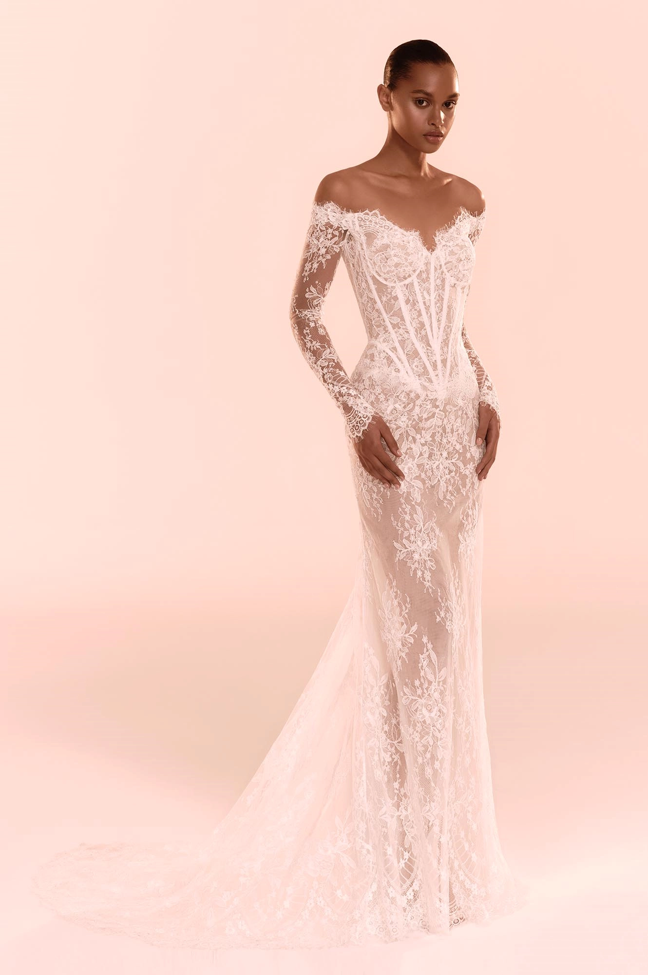 Zuhair Murad'ın couture işçiliğiyle hazırladığı, transparan ve omuzları açık dantel bir gelinlik modeli, vücuda oturan silueti, zarif çiçek işlemeleri ve uzun kuyruğuyla modern romantizmi vurguluyor.