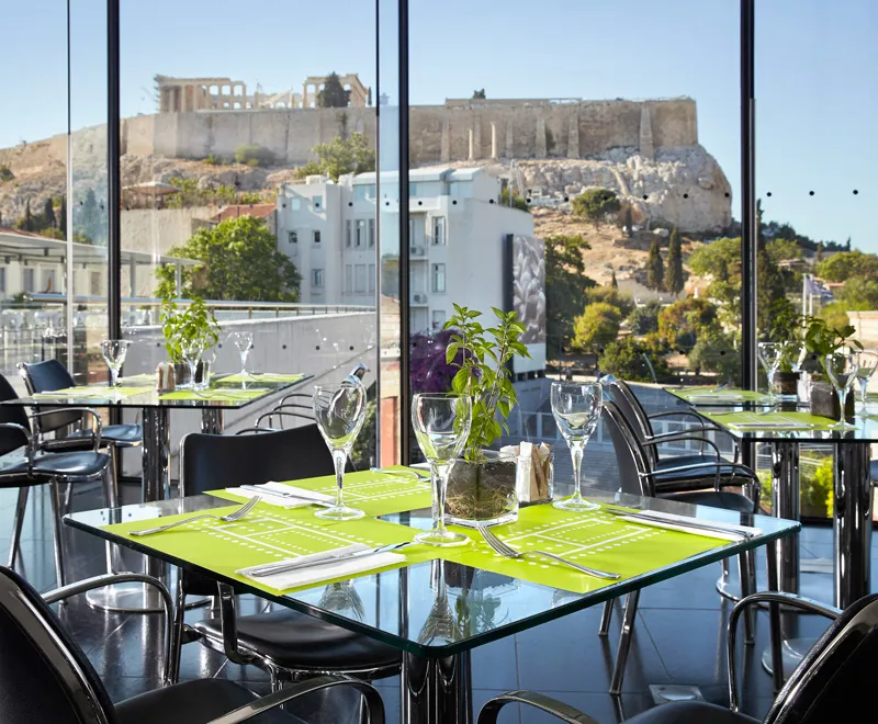 Atina'daki Akropolis Müzesi'nin modern restoranı, cam pencerelerinden eşsiz Akropolis manzarasına sahip, parlak yeşil Amerikan servisleri ve zarif kadeh takımlarıyla donatılmış şık masalarıyla, dünyanın en iyi müze restoranları arasında öne çıkan bir lezzet ve manzara deneyimi sunuyor.
