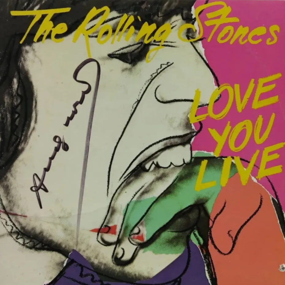 The Rolling Stones Love You Live albüm kapağı; neon sarı yazılar ve çizimlerle çevrili açık ağızlı yüz.