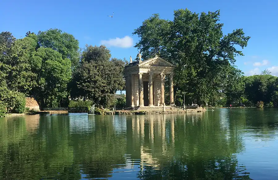 Villa Borghese'nin yemyeşil ağaçlarla çevrili göletinde, suyun berrak yansımalarıyla mistik bir hava katan, sağlık tanrısı Aesculapius'un heykellerinin süslediği sütunlu antik tapınak, Roma seyahat rehberimizin huzurlu duraklarından birini gözler önüne seriyor.