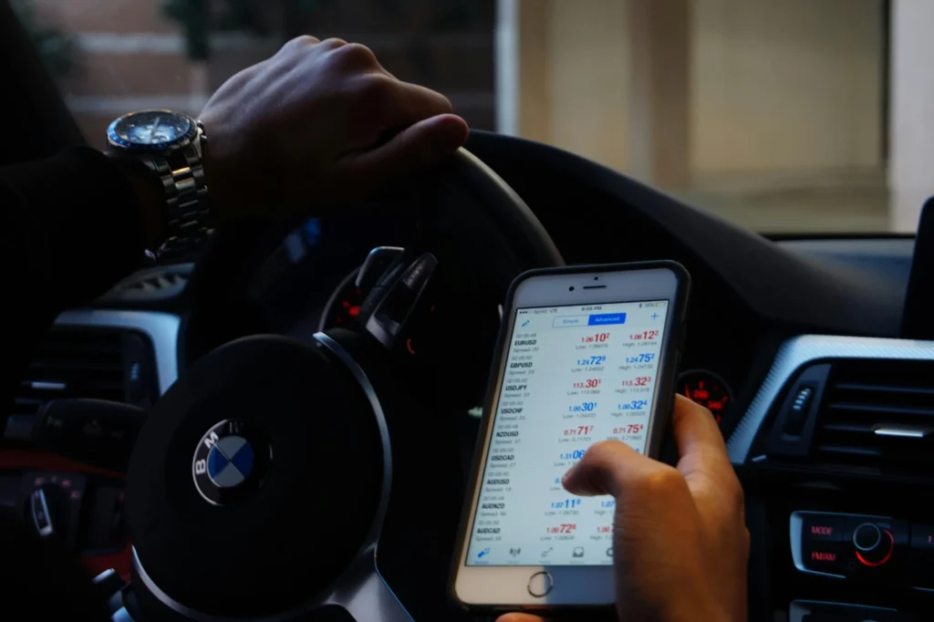 Bir sürücü, BMW aracının içinde döviz ve yatırım piyasalarını mobil uygulama üzerinden anlık olarak takip ediyor.