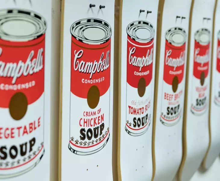 Campbell’s Soup Cans serisinden kırmızı ve beyaz konserve kutularının yan yana sergilendiği galeri detayı.