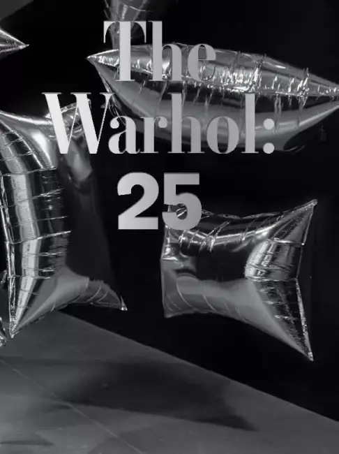 Andy Warhol Müzesi’nin 25. yılına özel tasarlanmış gümüş balonlar ve siyah arka plan üzerinde ‘The Warhol: 25’ yazısı; çağdaş sanat kutlaması.