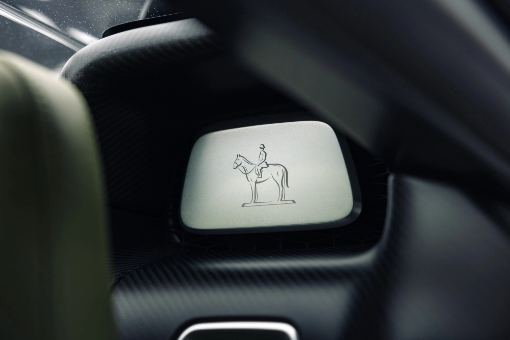 Bu yüksek değerli Bugatti Brouillard Programme Solitaire yeşil hiper otomobilin özel iç mekanında, karbon fiber dokulu yüzeyle çevrili şık bir panelde, zarif bir atlı binici figürü detayı görünüyor.