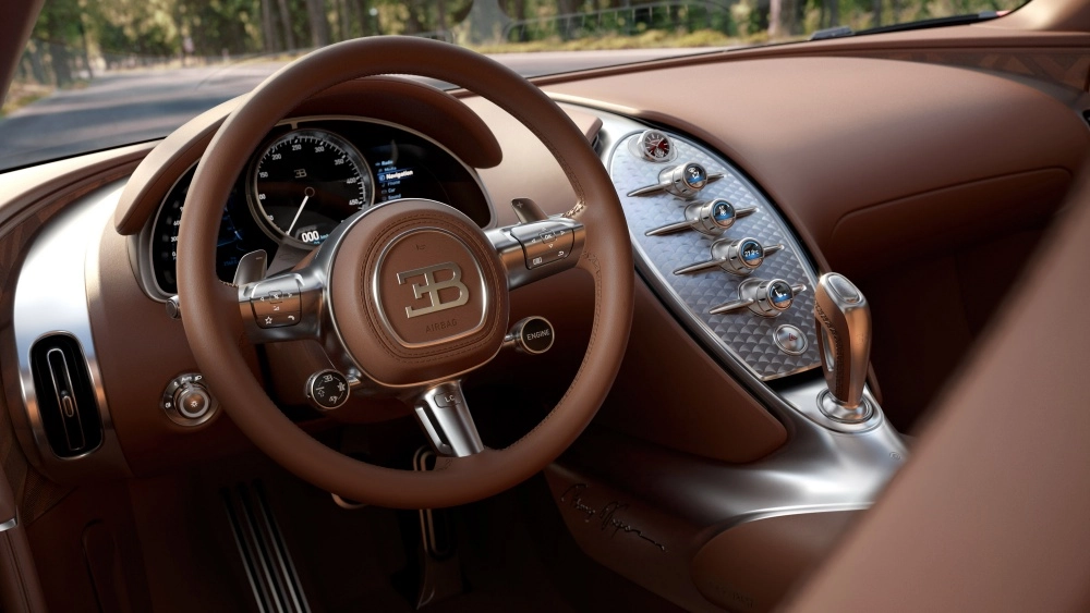 Bu görsel, Bugatti hiper otomobilin taba renkli deri direksiyonunu, metalik BB logosunu, gösterge panelini ve detaylı kontrol düğmeleriyle birlikte lüks iç mekan tasarımını yakından sergiliyor, aracın sofistike ve yüksek performanslı estetiğini vurguluyor.