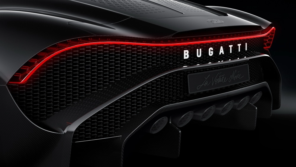 Siyah Bugatti La Voiture Noire hiper otomobilin çarpıcı arka tasarımı, boydan boya uzanan kırmızı LED stop lambası, karmaşık desenli ızgarası, karbon fiber detayları ve altı egzoz borusuyla, dünyanın en pahalı arabaları listesindeki yerini vurguluyor.