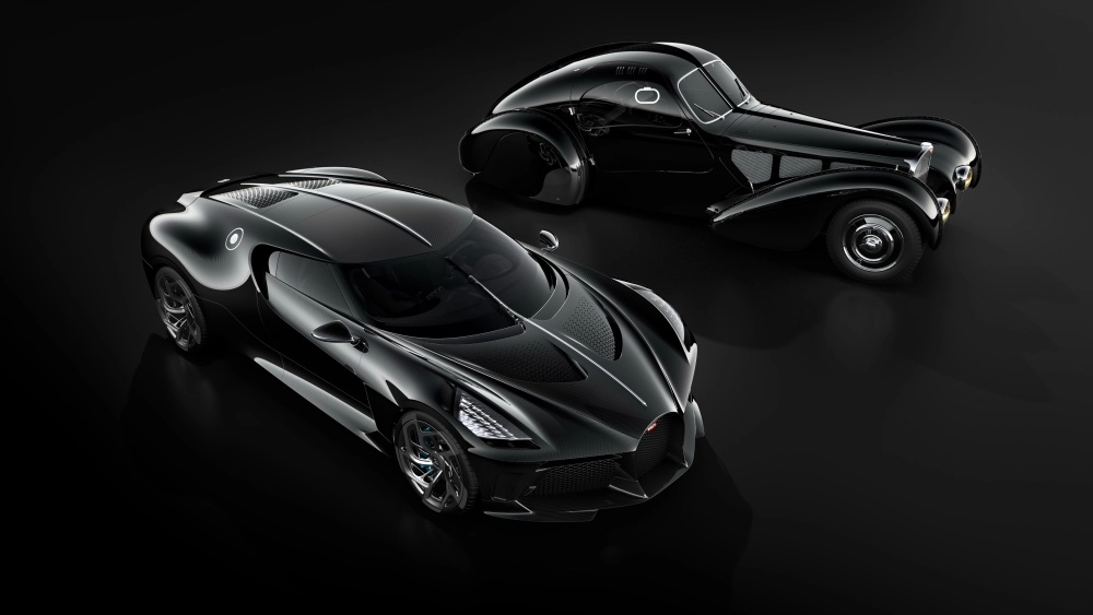 Modern, siyah, karbon fiber detaylara sahip Bugatti La Voiture Noire hiper otomobil ile arkada konumlanmış zarif klasik Bugatti Type 57 SC Atlantic'in şık birlikteliği, karanlık bir zeminde dünyanın en pahalı arabaları arasındaki eşsiz yerlerini sergiliyor.