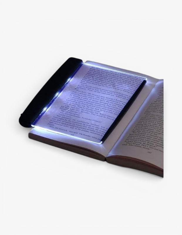 Açık bir kitabın üzerinde duran şeffaf LED panelli okuma lambası, sayfanın tamamını parlatarak yazıları netleştiriyor. Kitap severler için modern bir Sevgililer Günü hediye alternatifi.