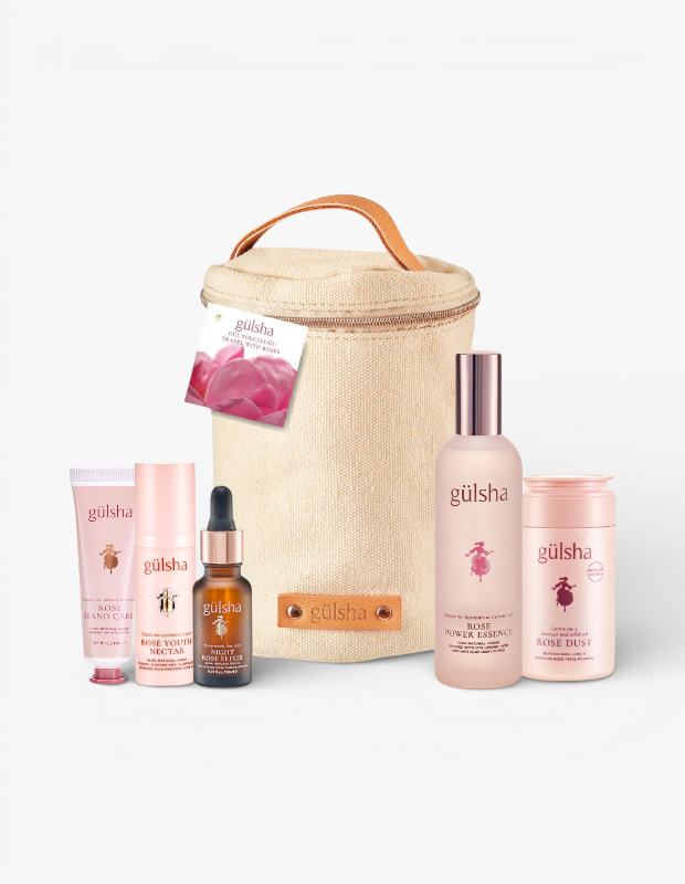 Sevgililer Günü hediye fikri olarak sunulan Gülsha seyahat seti. Bej rengi çantanın önünde Rose Power Essence, Rose Dust ve Night Rose Elixir gibi gül özlü cilt bakım ürünleri sergileniyor.