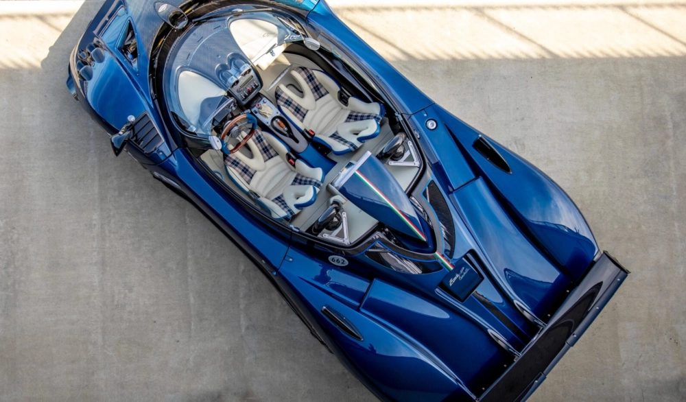 Parlak mavi Pagani Zonda HP Barchetta hiper otomobilin yukarıdan çekilmiş görüntüsünde, açık tavanı sayesinde krem rengi ve mavi ekoseli detaylara sahip el işçiliği iç mekanı, ahşap direksiyonu ve karbon fiber aksamları net bir şekilde görülmektedir.
