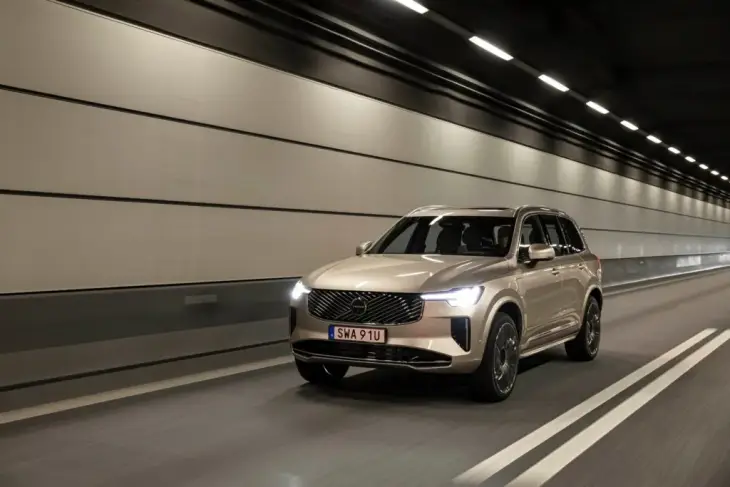 Modern ve aydınlık bir tünelde, yenilenen Volvo XC90 premium SUV, bej rengi kasası, parlak T şeklindeki farları ve yeni krom ızgarasıyla dinamik Tasarım ve etkileyici Performansını vurgulayarak hızla ilerliyor.