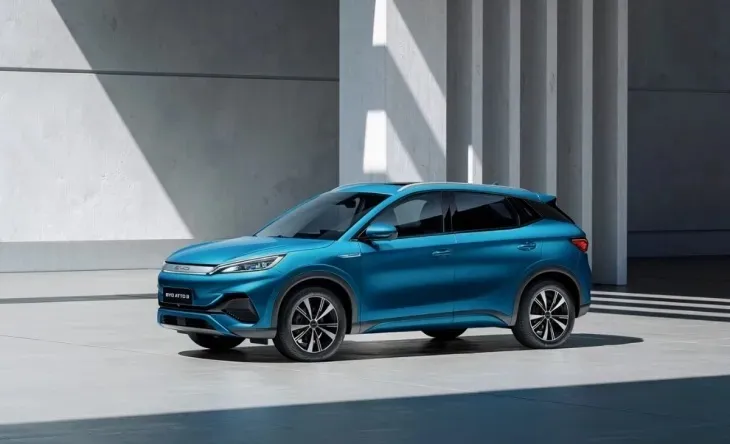 Mavi renkte bir BYD Atto 3 model elektrikli SUV, modern mimariye sahip bir binanın önünde park halinde duruyor. Binanın sütunlu ve sade tasarımı, aracın şık ve dinamik görünümünü vurguluyor.