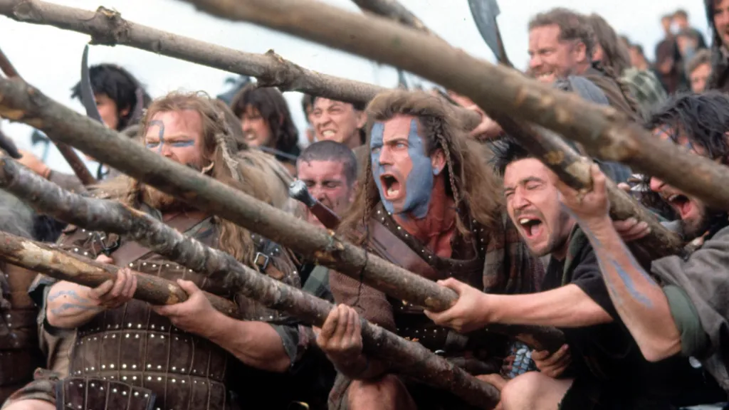 Cesur Yürek filminden, yüzleri boyalı İskoç savaşçıların mızraklarla saldırıya hazırlandığı destansı savaş sahnesi; ortada Mel Gibson yer alıyor.