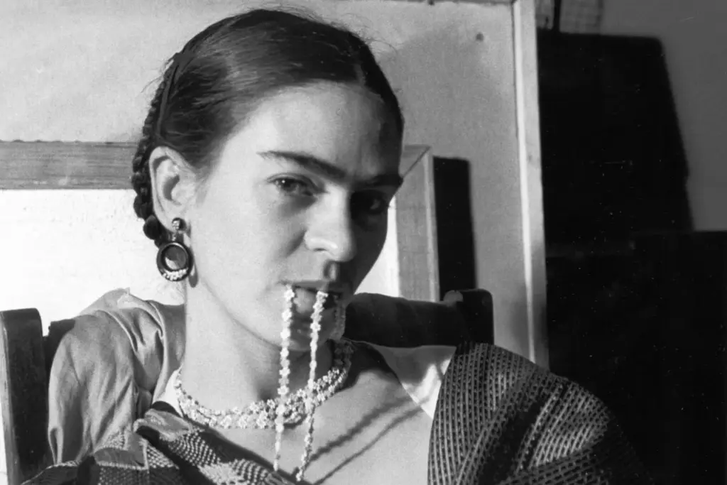 Frida Kahlo’nun ikonik siyah beyaz portresi, kolyesini dudaklarında tutarken objektife bakan Meksikalı ressam.