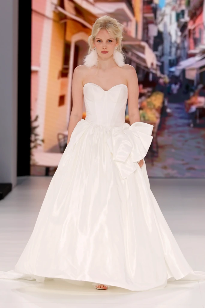Global Bridal House tasarımı, straplez kalp yaka, büyük fiyonklu ve kabarık etekli zarif gelinlik modeli.