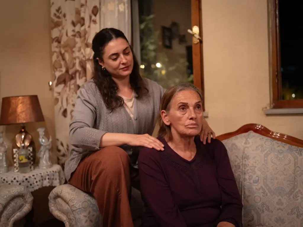 Görselde, Prime Video platformunda izlenebilecek Mukadderat filminin duygusal bir anından: hüzünlü görünen yaşlı bir kadının omzuna şefkatle dokunarak destek olan genç bir kadın, içten bir dayanışma ve ailevi bağı vurguluyor.
