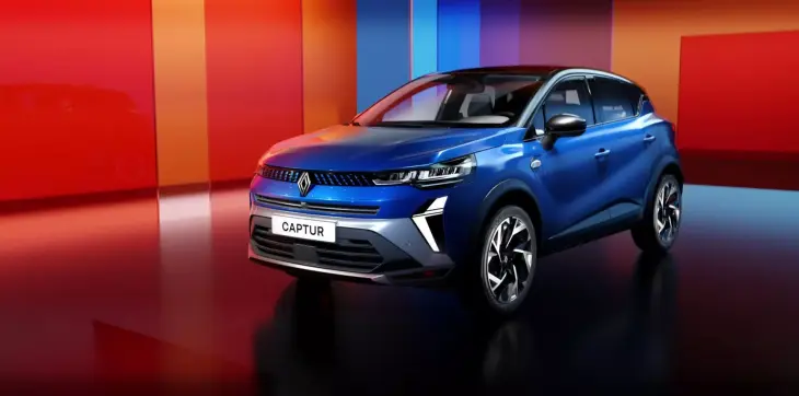 Mavi renkte bir Renault Captur model araba, modern bir stüdyo fonunun önünde duruyor. Arka planda turuncu ve mavi tonlarda çizgiler ve yansımalar görülüyor.