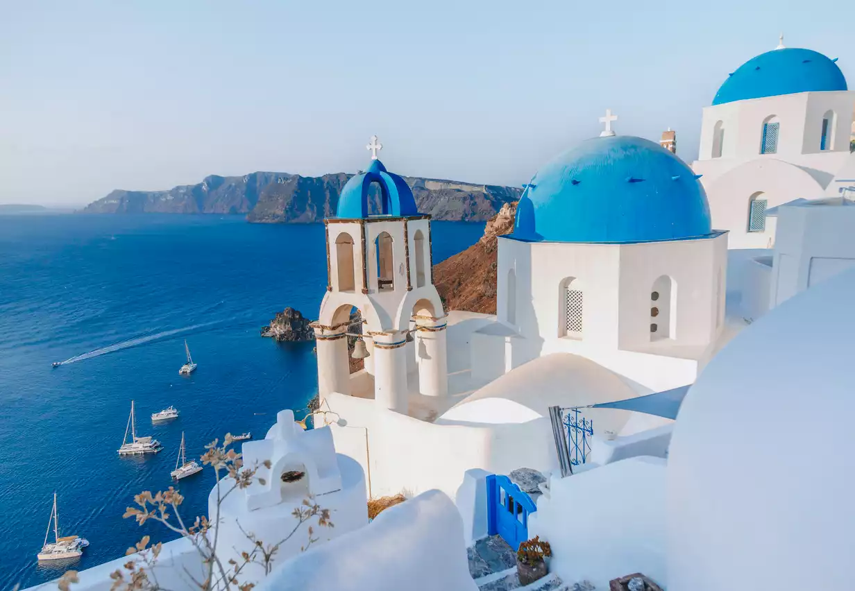 Santorini'nin sarp yamaçlarında konumlanmış, beyaz badanalı evleri, masmavi kubbeli kiliseleri ve çan kulesiyle Akdeniz'in en güzel şehirleri arasında parlayan bu rüya gibi manzara, açık denizde yüzen yelkenli teknelerle ve uzaklardaki adaların silüetiyle tamamlanıyor.