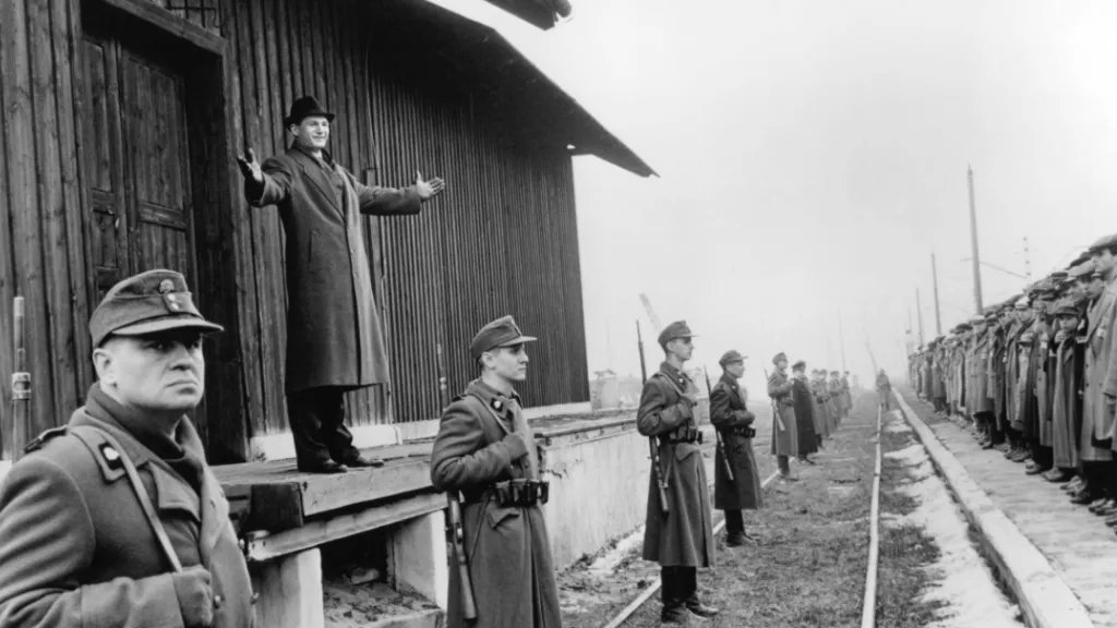 Naziler tarafından toplama kampına götürülen Yahudiler, Schindler’in Listesi filminden siyah-beyaz dramatik bir sahne.