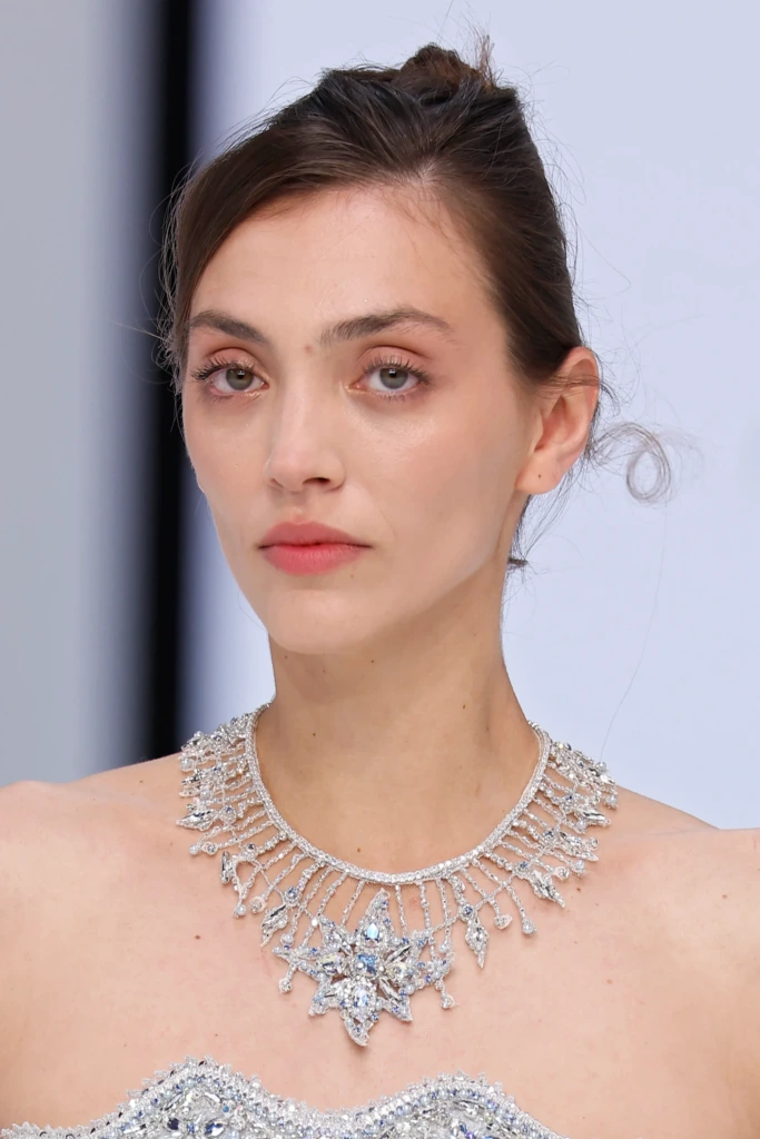 The Atelier by Jimmy Choo 2026 koleksiyonuna ait, gelinlik ile uyumlu olarak tasarlanmış yıldız formlu büyük taşlı gerdanlık; zarif, romantik ve dikkat çekici bir gelin takısı örneği.