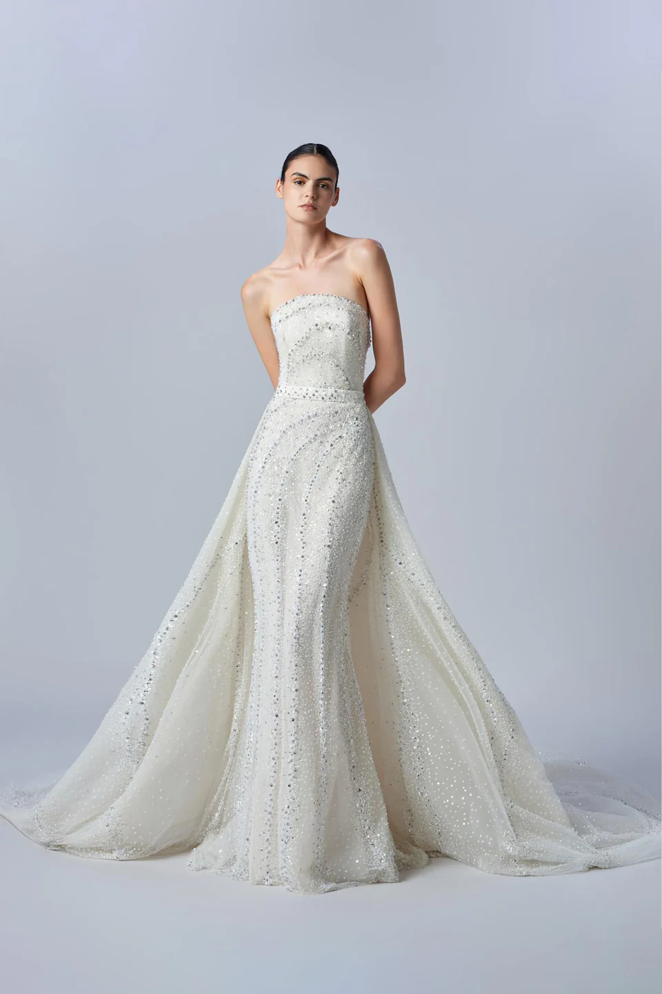 Elie Saab straplez düz yaka, tamamı gümüş ışıltılı dalga formlu kristal ve boncuk işlemeli, belden eklenen hacimli pelerin etek detaylı balık model gelinlik.