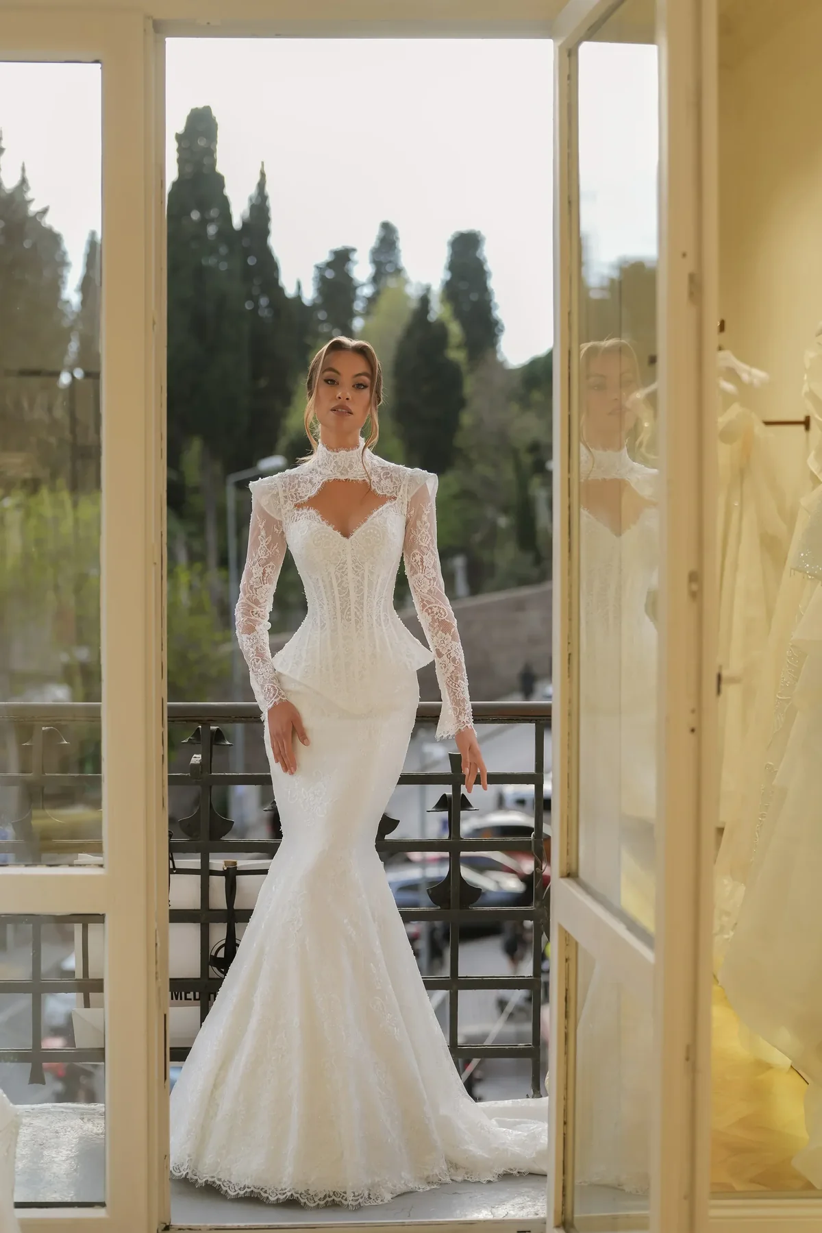 Mediha Cambaz yüksek dantel yakalı, pencereli dekolte detaylı, uzun dantel kollu ve belden peplum formlu korse büstiyerli balık model gelinlik.