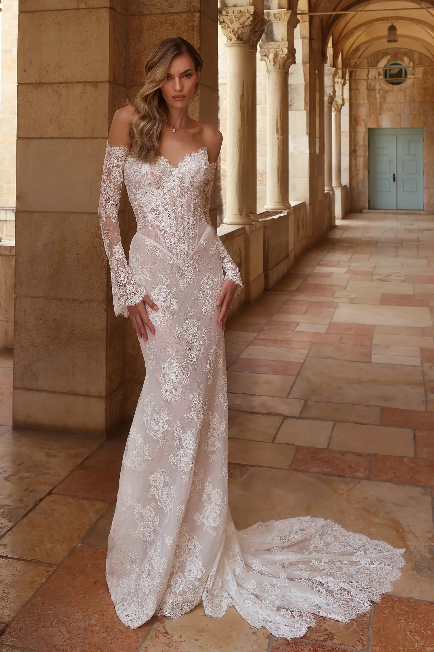 Pnina Tornai düşük omuzlu, kalp yaka, uzun dantel kollu, gövdesi belirgin korse yapısında ve tamamı vintage dokulu floral dantel kaplamalı balık model gelinlik.