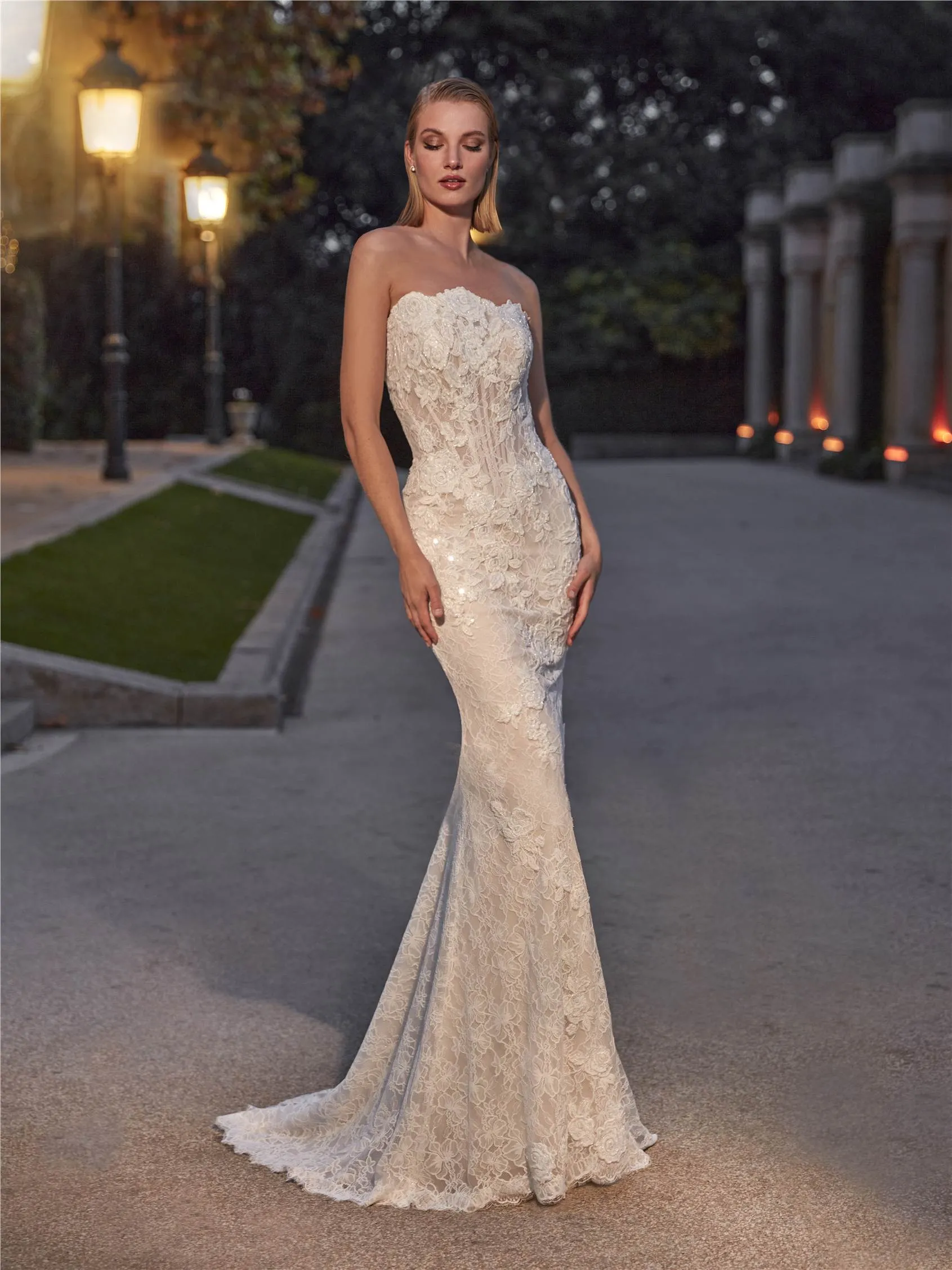 Pronovias Priveé straplez kalp yaka, gövdesi transparan korse yapısında, tamamı ince floral dantel işlemeli ve hafif parıltılı dokuya sahip, vücudu saran balık model gelinlik.