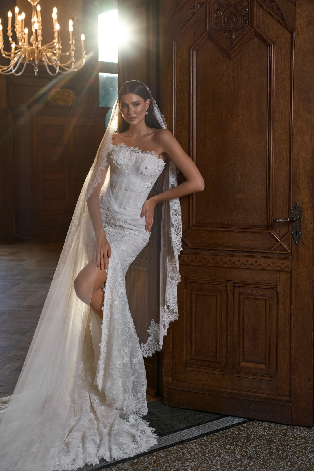 Sima Couture straplez, göğüs kısmı asimetrik tül drapeler ve ince dantel biyelerle detaylandırılmış, derin bacak yırtmaçlı ve tamamı Fransız danteli kaplı, kenarları dantel işlemeli uzun tül duvaklı balık model gelinlik.