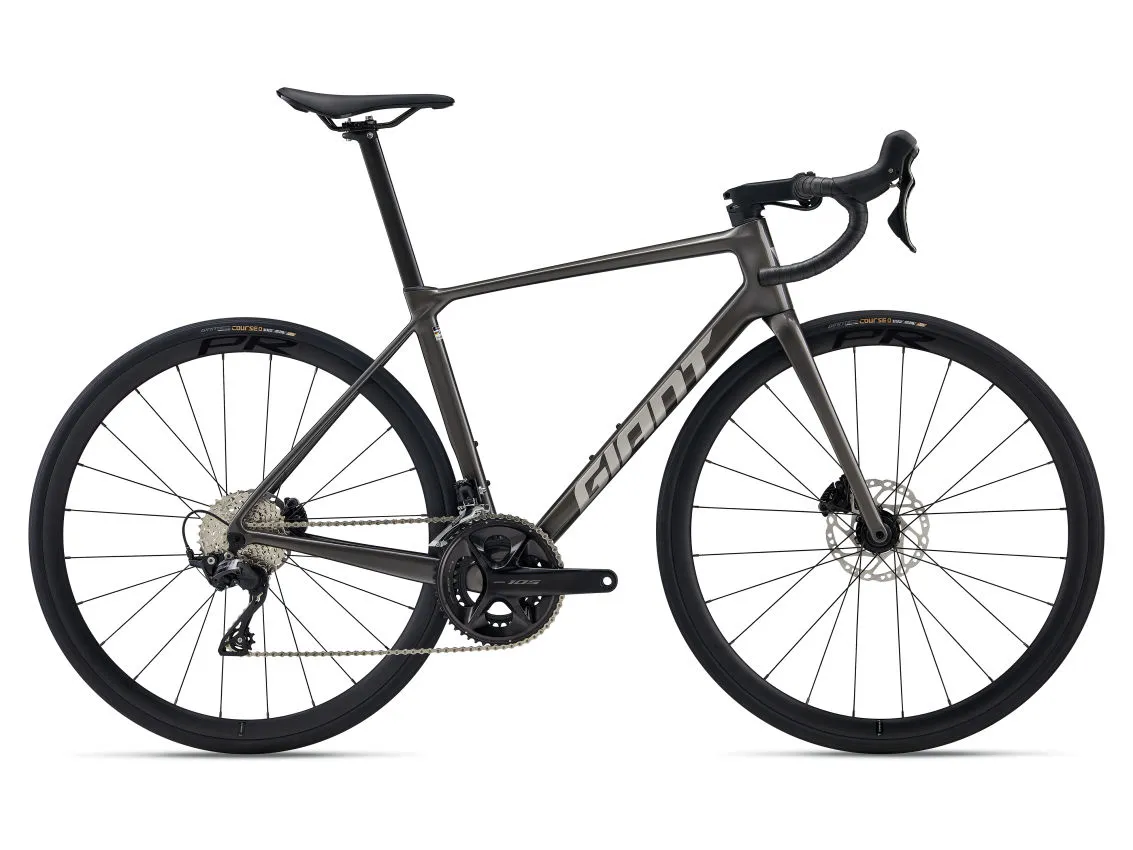Beyaz arka plan üzerinde duran, zarif koyu gri renkteki Giant TCR yol bisikleti, entegre kablolama ve aerodinamik bir kadro tasarımına sahip olup, Shimano 105 grup set ile donatılmış disk frenli tekerlekleriyle dikkat çekiyor.