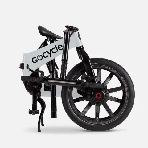 Sade beyaz bir arka plan önünde katlanmış halde duran Gocycle G4i elektrikli bisiklet, beyaz ana gövdesi, siyah detayları ve kendine özgü jant tasarımıyla dikkat çekerek kompakt ve modern şehir içi ulaşım çözümünü gözler önüne seriyor.