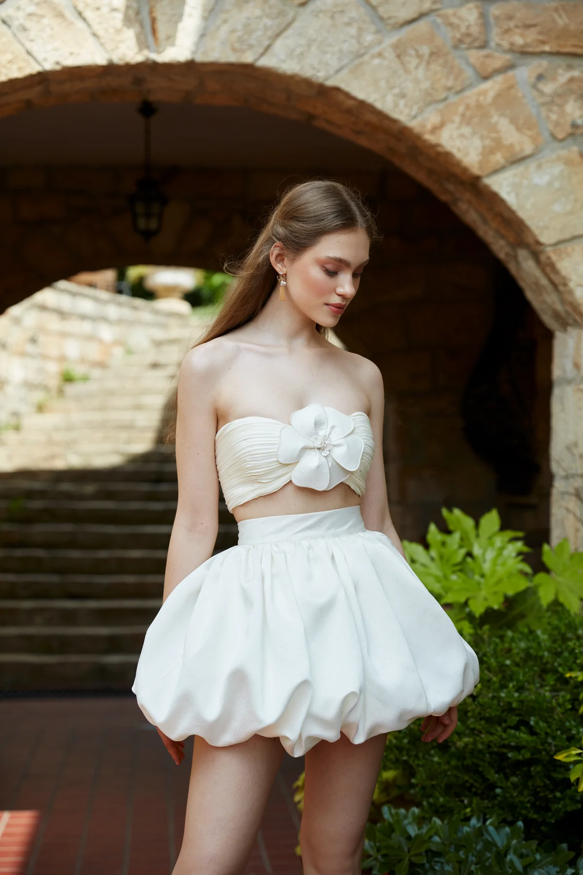 Glamyou Bridal by Tuvanam iki parçalı mini gelinlik; göğüs kısmında büyük çiçek detayı bulunan straplez büstiyer ve kabarık formlu mini balon etek.
