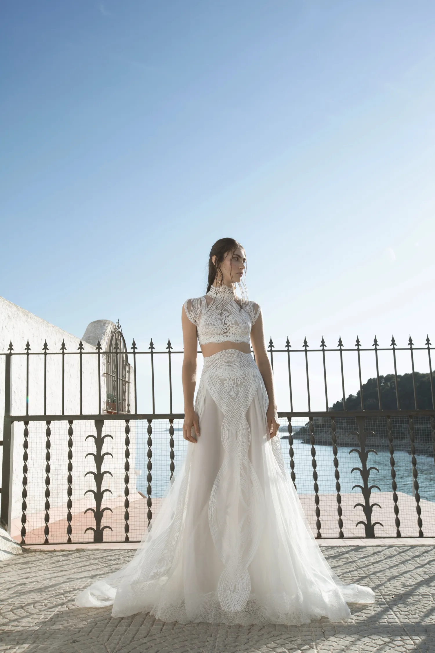 Yolancris Origins koleksiyonu iki parçalı bohem gelinlik; yüksek yaka dantel işlemeli crop top ve geometrik dantel detaylı vual A-kesim etek.