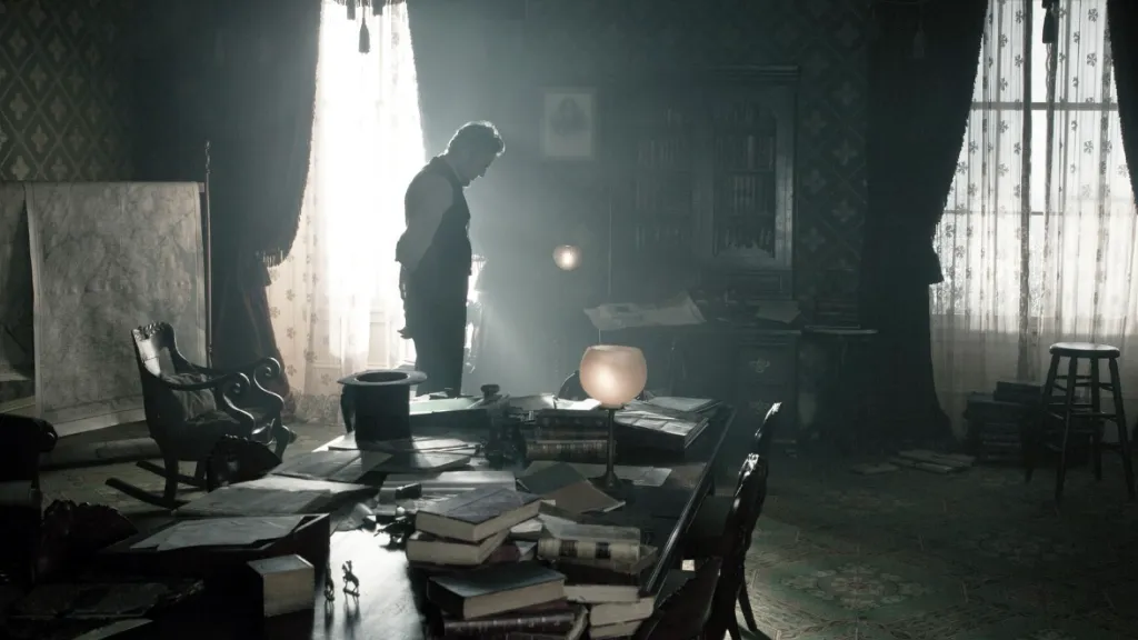 Lincoln (2012) filminden dramatik iç mekân sahnesi: Loş bir odada, arka plandaki dantel perdelerden süzülen gün ışığı bir adamın (muhtemelen Abraham Lincoln) silüetini aydınlatıyor. Masanın üzeri dağınık şekilde kitaplar ve belgelerle dolu, ortam tarihi ve entelektüel bir atmosfer yayıyor. Görsel, dönemin politik yükünü ve karakterin içsel çatışmasını yansıtan bir sinematografiyle çerçevelenmiş.