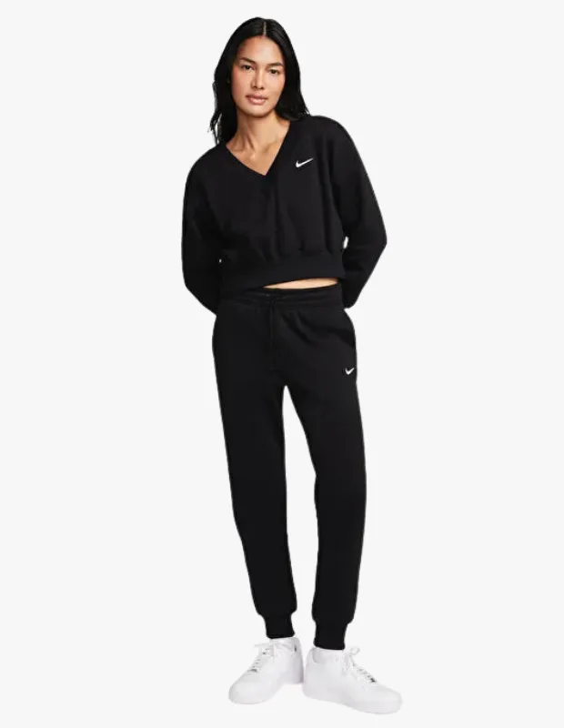 Siyah, V yaka kısa sweatshirt ve lastikli bel eşofman altından oluşan, rahat ve şık bir Nike takım giyen, beyaz spor ayakkabılı bir kadın, Anneler Günü’nde annenize özel hissettirecek ve onun stilini tamamlayacak harika bir hediye alternatifi sunuyor.