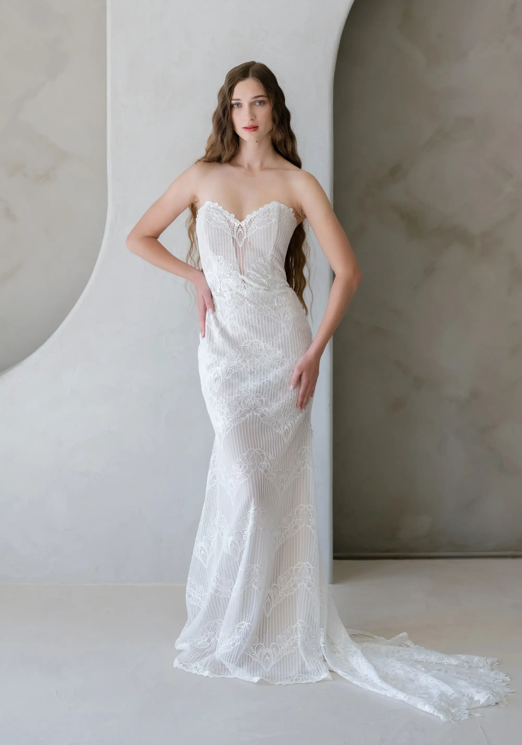 Straplez, dantel işlemeli Claire Pettibone gelinlik; ince askısız korsaj ve vücuda oturan zarif kesimiyle sade ve romantik bir görünüm.
