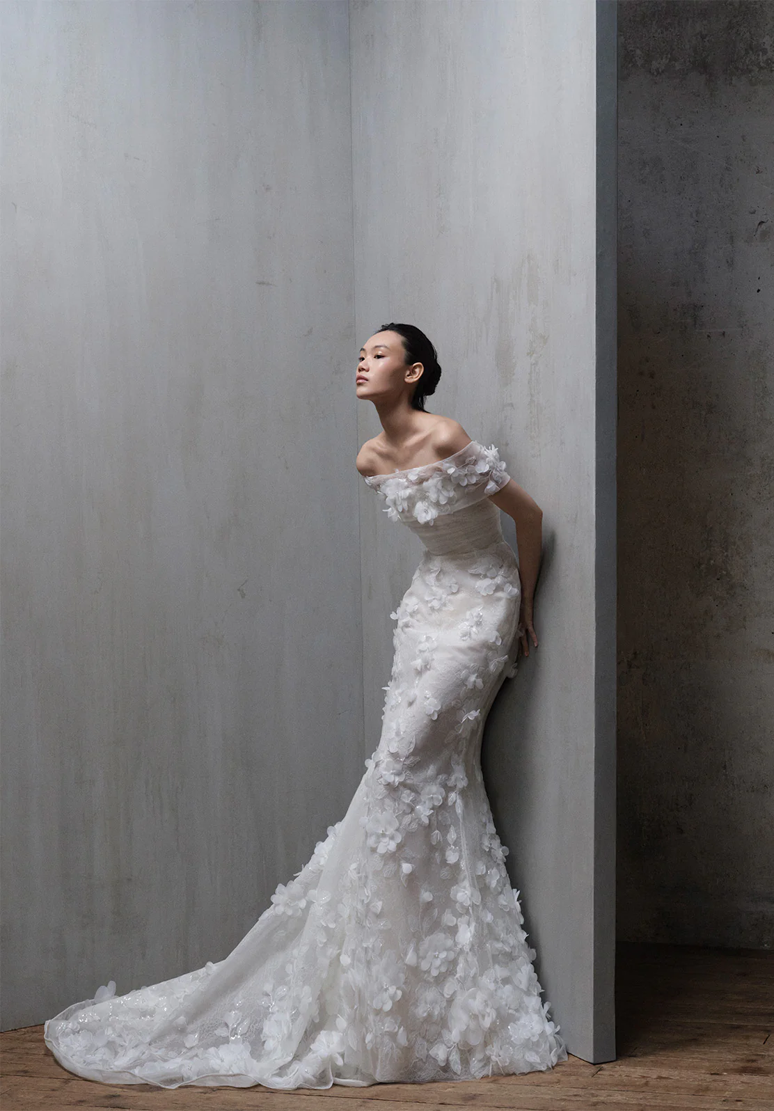 Elie Saab 2026 sonbahar koleksiyonundan üç boyutlu çiçek aplikeli, düşük omuzlu, balık kesim romantik gelinlik.