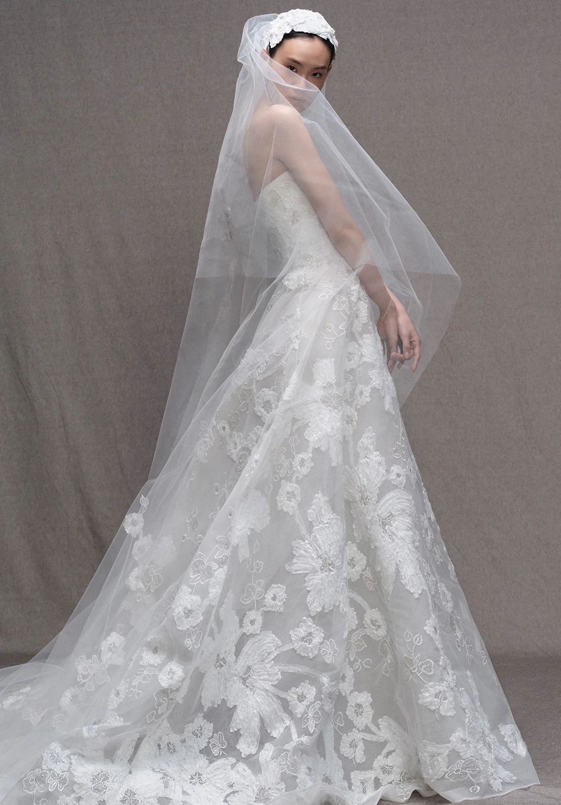 Elie Saab 2026 sonbahar koleksiyonundan straplez, çiçek işlemeli dantel, uzun duvaklı zarif romantik gelinlik.