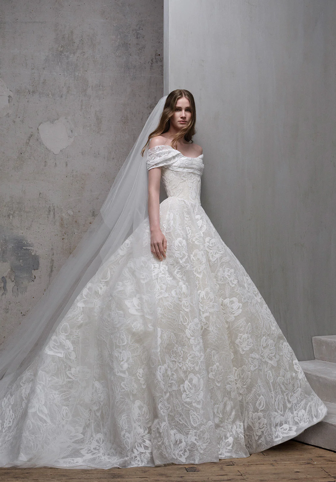 Elie Saab 2026 sonbahar koleksiyonundan düşük omuzlu, çiçek motifli dantel, uzun duvaklı klasik romantik balo gelinlik.