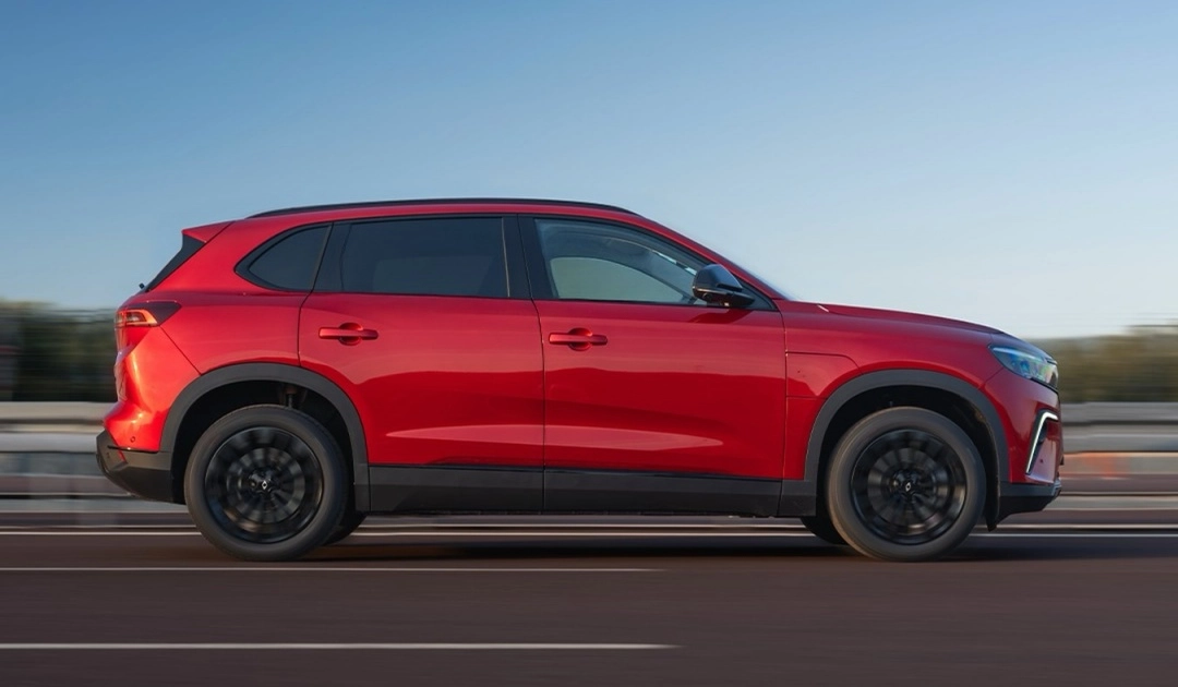 Kırmızı renkli Togg T10X SUV, siyah jantları ve alt gövde kaplamalarıyla bir yolda sağa doğru hızla ilerlerken, çift motorlu ve 435 beygir gücündeki performansını ima eden dinamik bir duruş sergiliyor.
