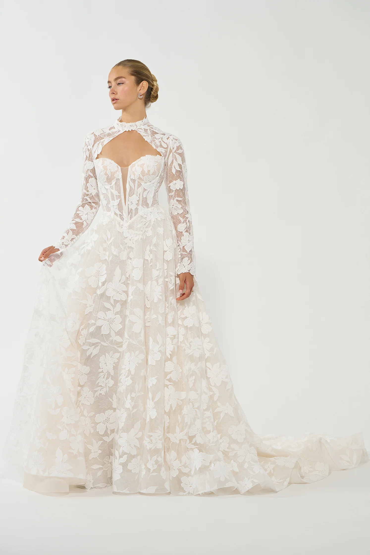 Allure Bridals marka, zarif çiçek motifleriyle işlenmiş transparan dantelli, yüksek boyunlu ve dekolteli modern üst kısmı olan uzun kollu beyaz gelinlik.