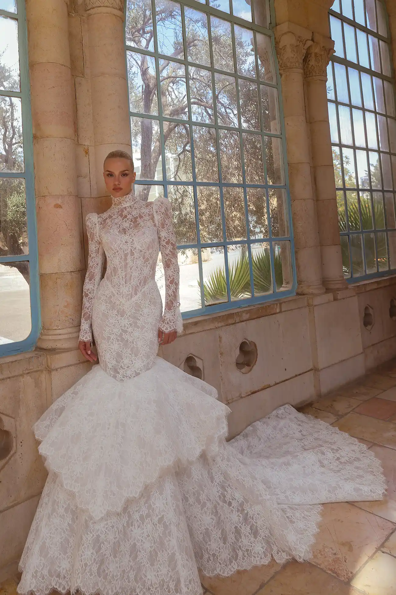 Pnina Tornai yüksek yakalı, uzun kollu, dantel işlemeli ve katlı etekli balık model gelinlik.