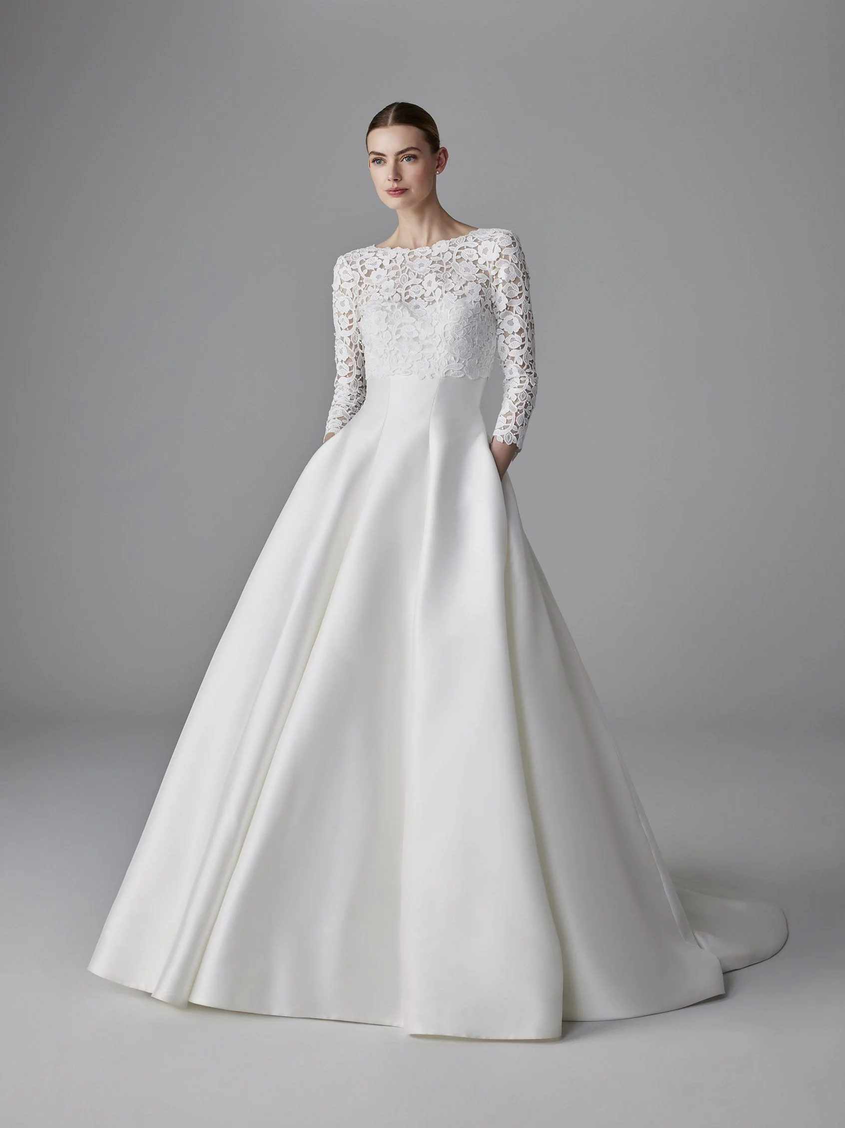 Pronovias 3/4 kollu, kayık yakalı, dantel büstiyerli ve saten etekli A-kesim gelinlik.