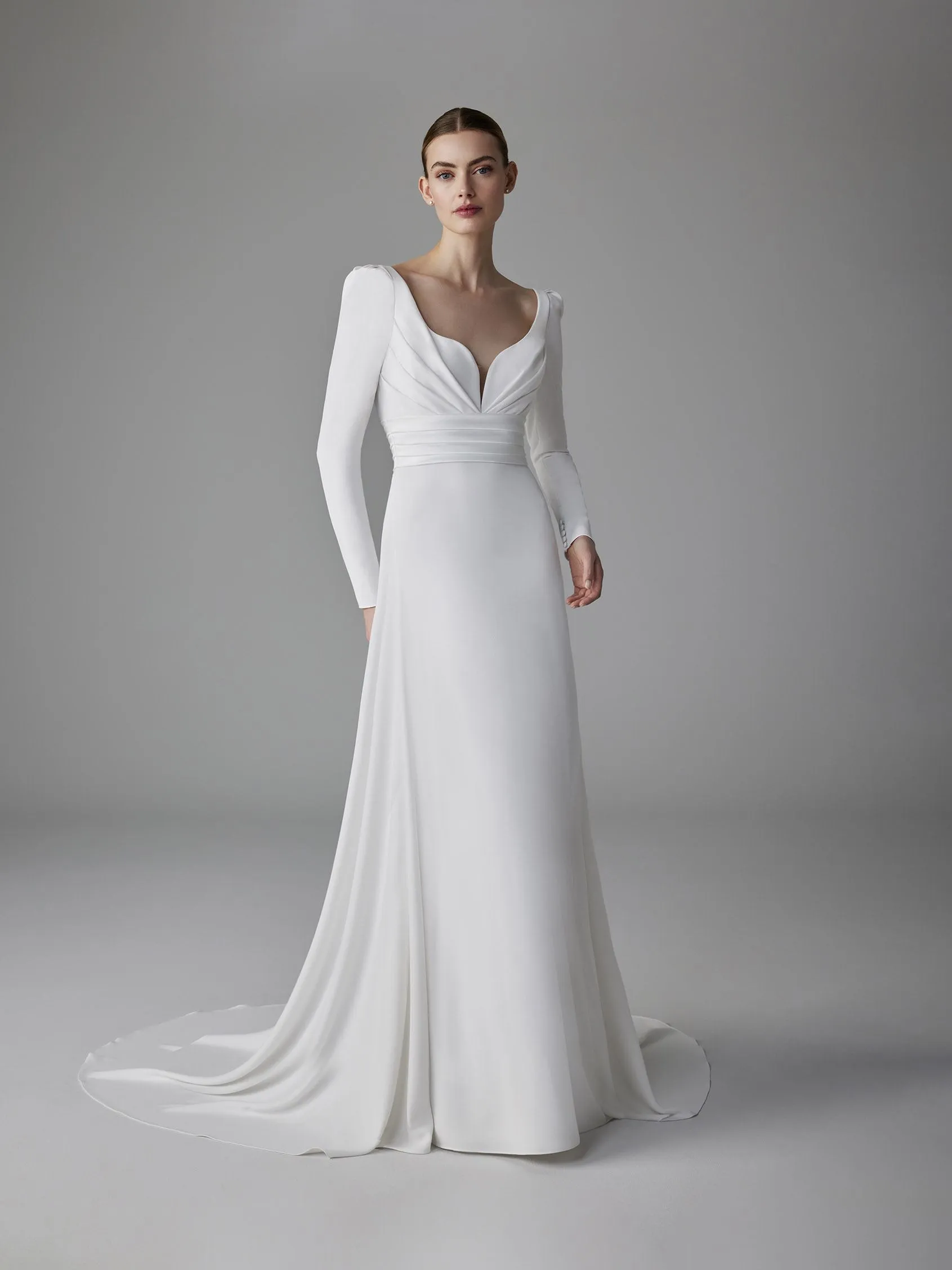 Pronovias uzun kollu, derin V yakalı, belden drapeli ve sade saten balık model gelinlik.